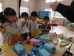 写真：うさぎ組の子どもたちが、初売りごっこで並んだ手作りおもちゃを選んでいるところ