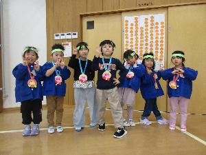 写真：ゲーム大会後にゲームキャラクターがデザインされたメダルをもらい、得点版の前で写真撮影をする子どもたち