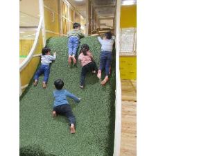 写真：ふかふかの人工芝の坂をよじ登る、5人の子どもたち