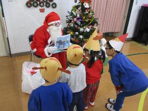 写真：サンタさんに質問をする子どもたちの様子。椅子に座るサンタさんの隣にクリスマスツリーが飾られています。