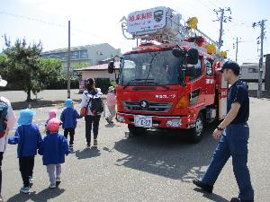写真：はしご消防車の周りを消防士さんと歩き、見学する子どもたち