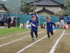 小学校の校庭のコースを並んで走る5歳児2人の様子