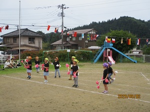 写真：年長児がポンポンのついたバチを持って、遊戯を披露している様子