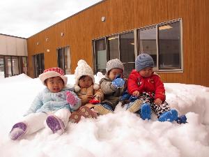 写真：テラスにできた雪山の上に座るひよこ組4人の子どもたち