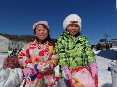 写真：雪遊びで女の子2人が容器に雪とピンクの色水を入れて嬉しそうに見せているところ