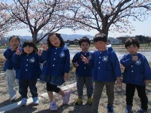 写真：青空の下、満開の桜の木の前でポーズを決めている男の子と女の子