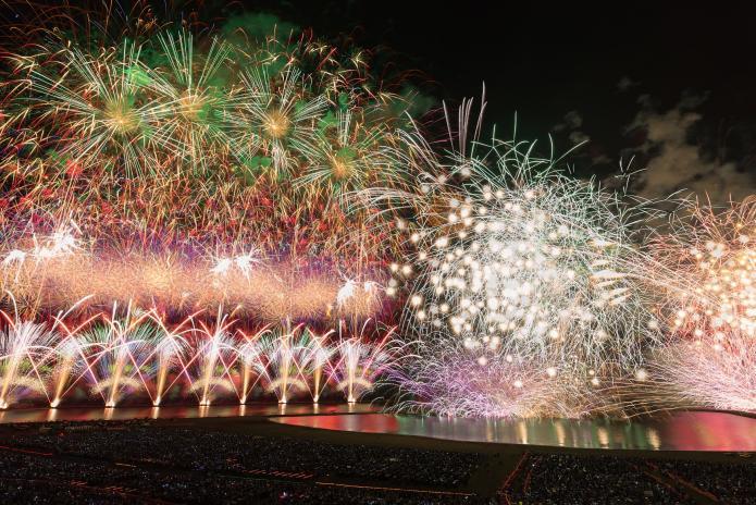 海中空スターマインが打ち上げられている海の大花火大会の様子の写真