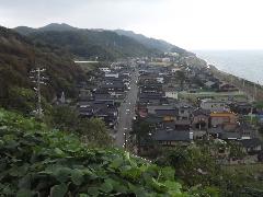 海岸線と米山が背後に佇む江戸時代に宿場町として栄えた面影を残す鉢崎の町並みの写真