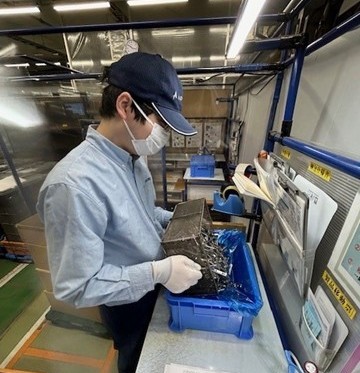 写真：たくさんのねじを箱にあける男性が写っています