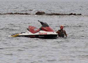 水上バイクを歩いて牽引する男性ライフセーバー