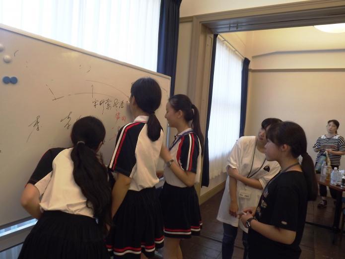 ホワイトボードを使って、中国語や英語で出し物の相談をする両国の中学生