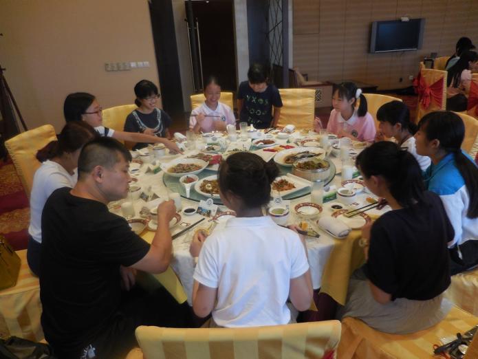 たくさんの料理が並んだテーブルを囲んで、両国の中学生が楽しく会話をしている様子の写真