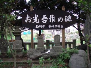 緑の木々に囲まれた石碑の近くに、「お光・吾作の碑」という看板を掲げている写真
