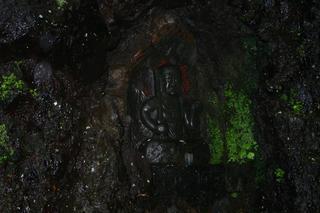 滝の流れる岩窟に鎮座する不動明王石像の写真