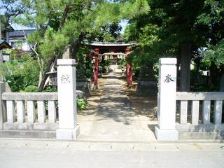 松の木と石門があり、その奥には参道と鳥居、社殿が建つ三島神社入口の写真