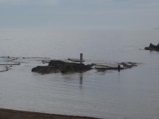 浜辺にある岩場に石碑が立っている写真