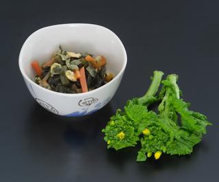野沢菜の塩漬けと打ち豆、人参と一緒に煮た栄養満点の小鉢に白い盛られた煮菜の写真