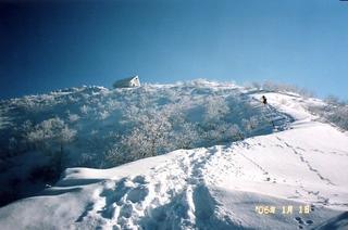 1月に水場付近から撮影した青空の下に白銀の雪が降り積もった米山山頂の写真