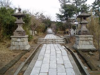 自然に囲まれた社殿まで長く続く石畳で造られた御島石部神社参道の写真