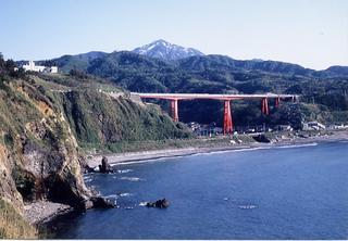 手前には日本海が広がり、赤い橋脚の米山大橋と米山の雄姿の写真