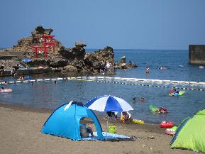 青い海水がきれいな小さめのビーチにたくさんの人が楽しんでいる写真