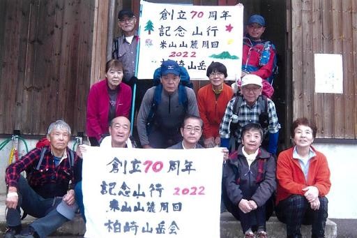 柏崎山岳会創立70周年記念の集合写真。11人の男女会員が笑顔で写っています