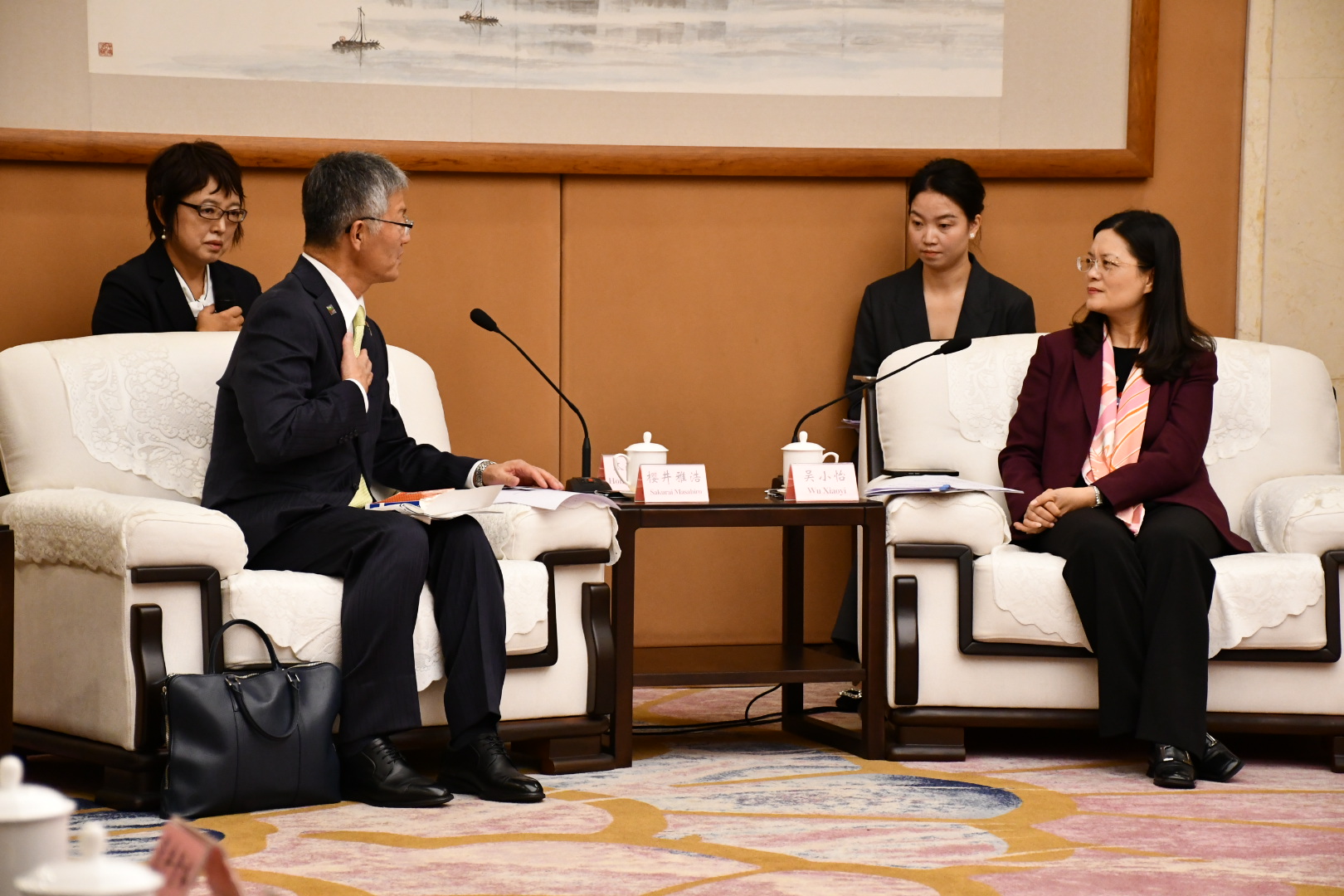 写真：左側に柏崎市長が、右側に楽山市長が座り、会談を行っています。その後ろにはそれぞれの通訳がいます