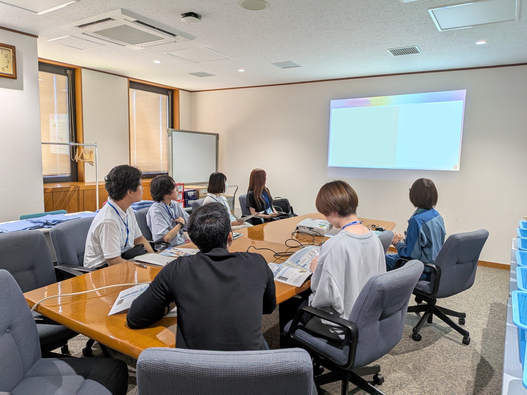 写真：明るい内容の会議室で、発電所の説明を受ける学生たち