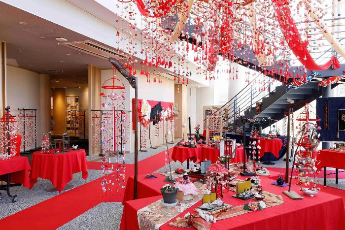 写真：昨年のつるし雛かざりの様子。毛せんを敷いたテーブルや天井から、たくさんのつるし雛が飾られています