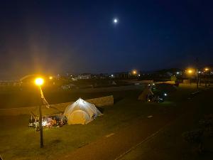 写真：夜のキャンプエリア。夜空に満月が浮かび、テントが2張り写っています