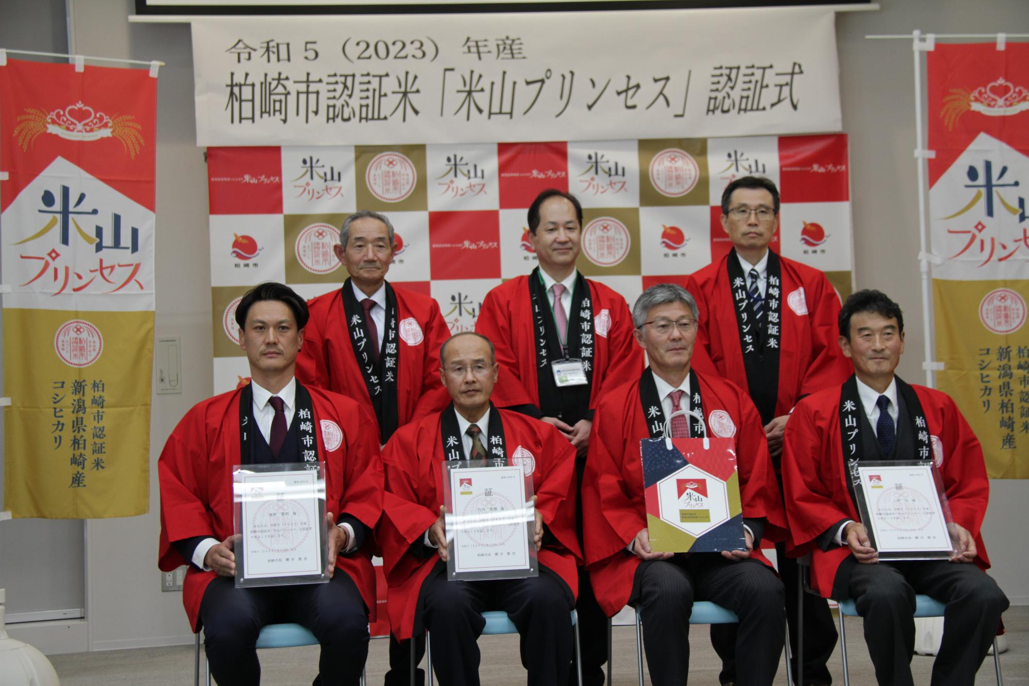写真：3人の認証者と、櫻井市長をはじめとした関係者が記念のカメラに収まりました。全員が米山プリンセスの赤い法被を着用しました。