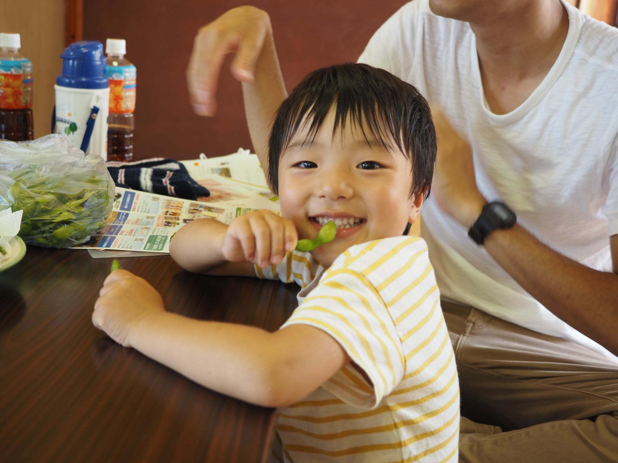 参加者+の子供が試食用の枝豆を食べている写真