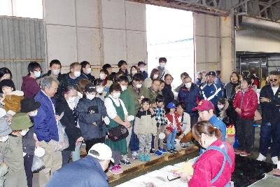 写真：競りに参加するお客さんたち。競り人の前には商品が並べられています。