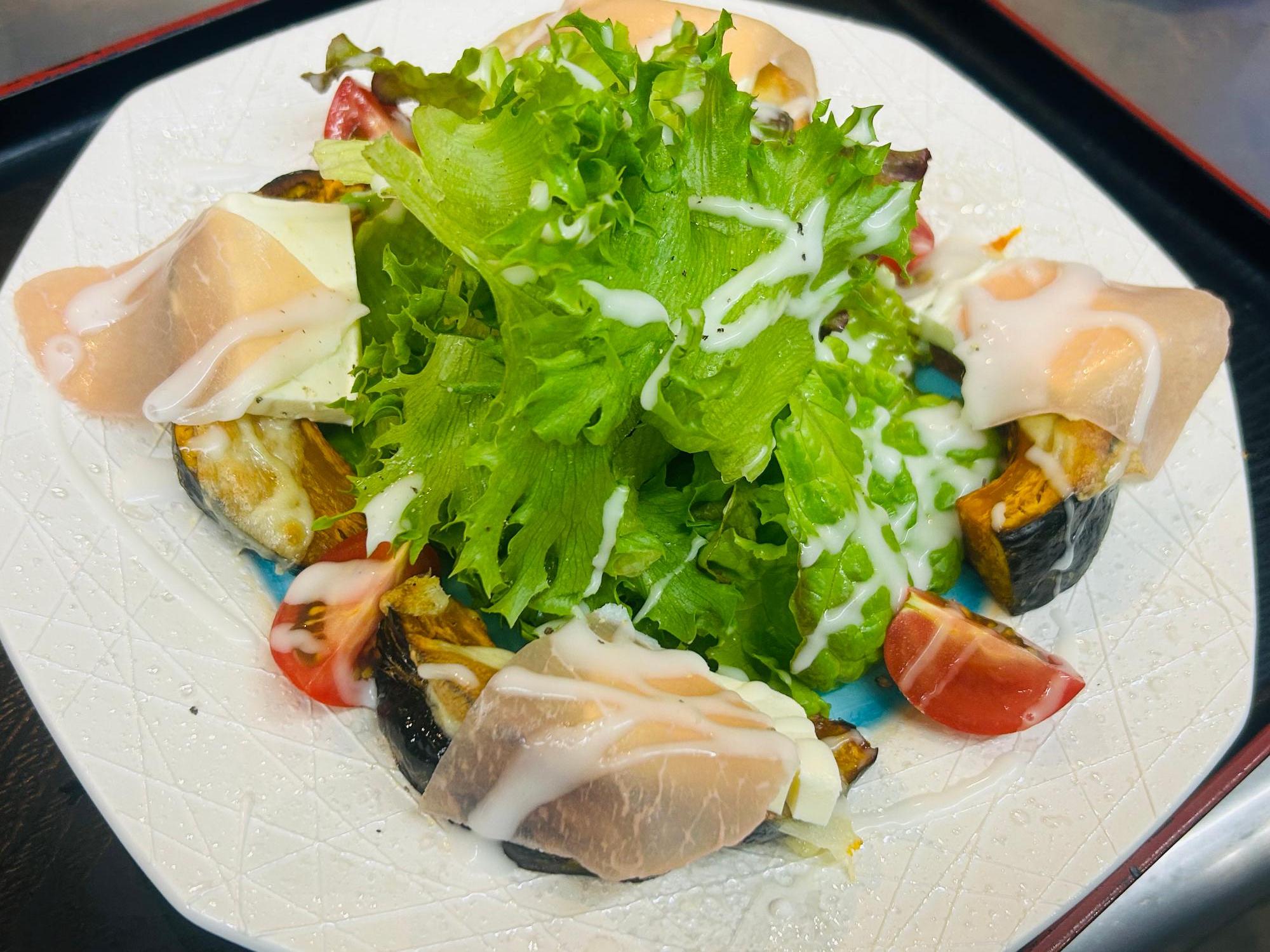 写真：焼いたかぼちゃや生ハムの上にクリームチーズのドレッシングをかけたサラダ