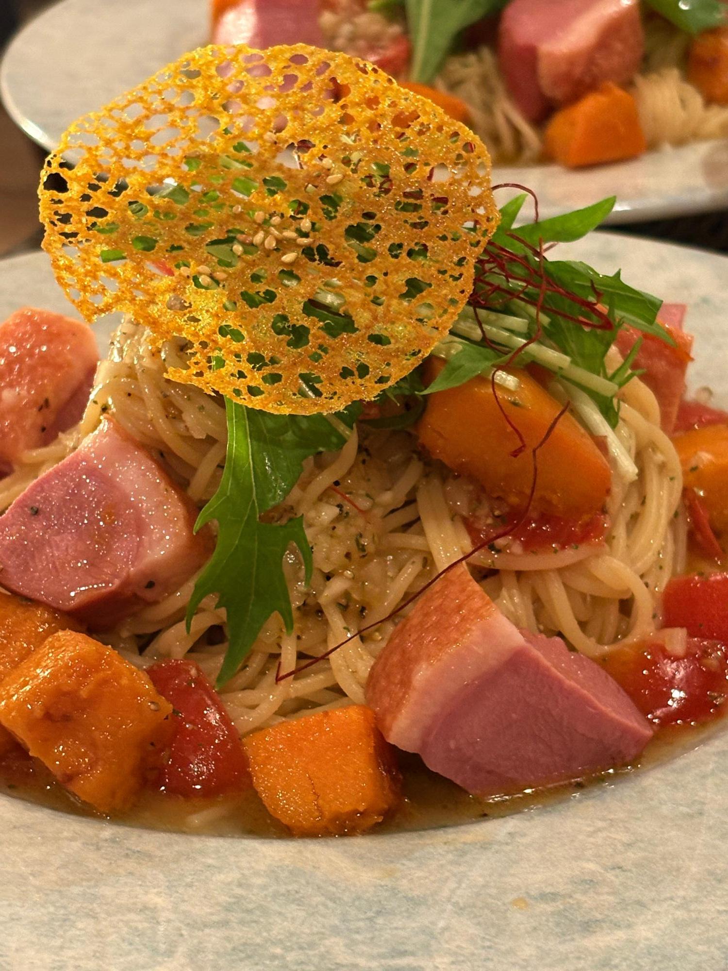 写真：角切りのかぼちゃと鴨肉が入ったパスタ。水菜や糸唐辛子焦がしチーズがトッピングされています