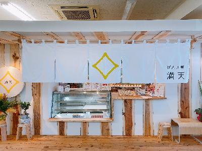 ぱん工房満天のお店の中です。木材を使用した内観に白い大きなのれんがかけられています。