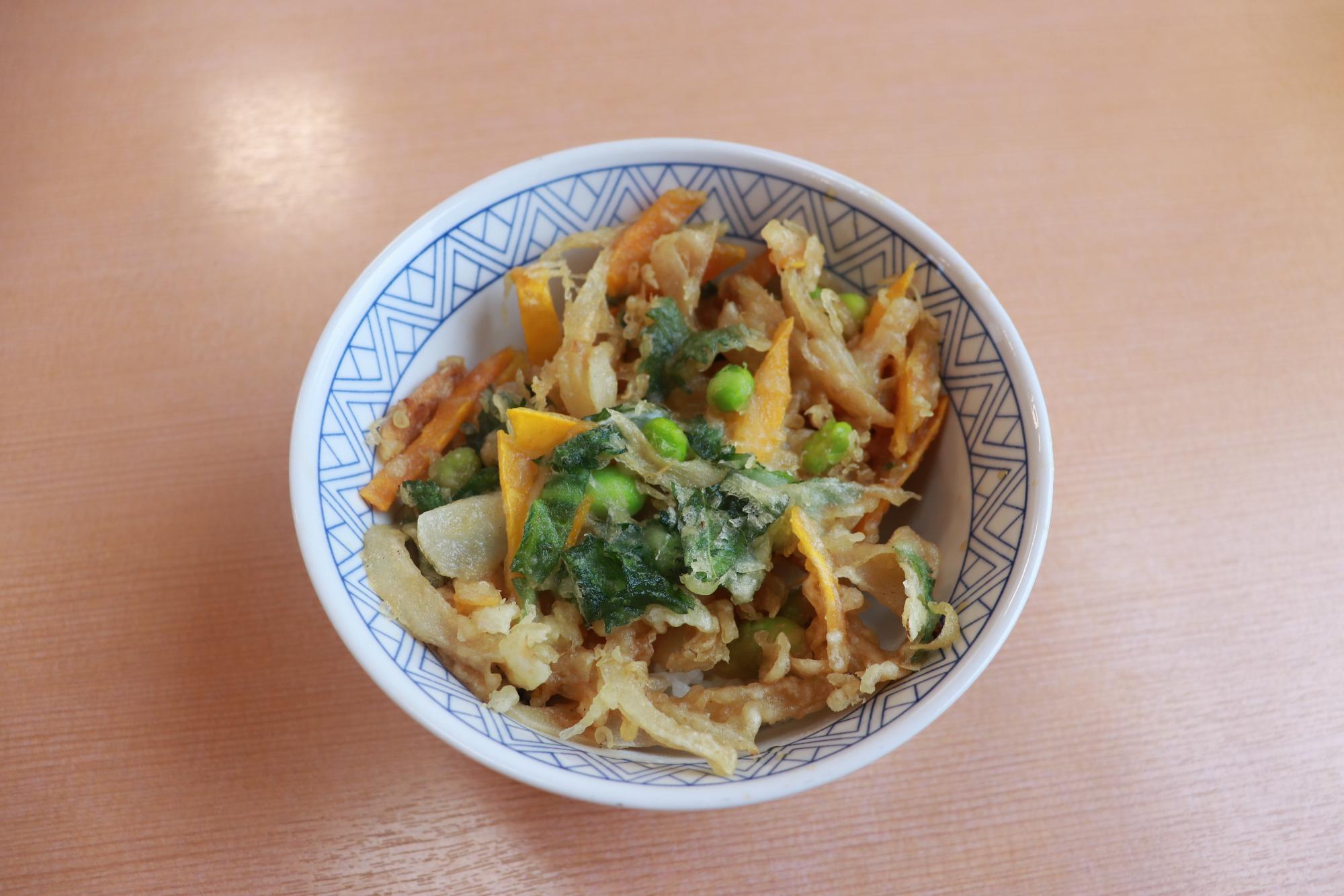 写真：かぼちゃと枝豆の入った大きなかき揚げがご飯の上にのっています