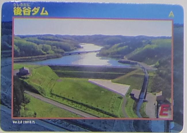 後谷ダムのダムカードの写真。ダム全体が写り、手前に管理道路が走っています。
