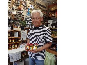 池田養蜂の池田三一さんが蜂蜜を持っている写真です。