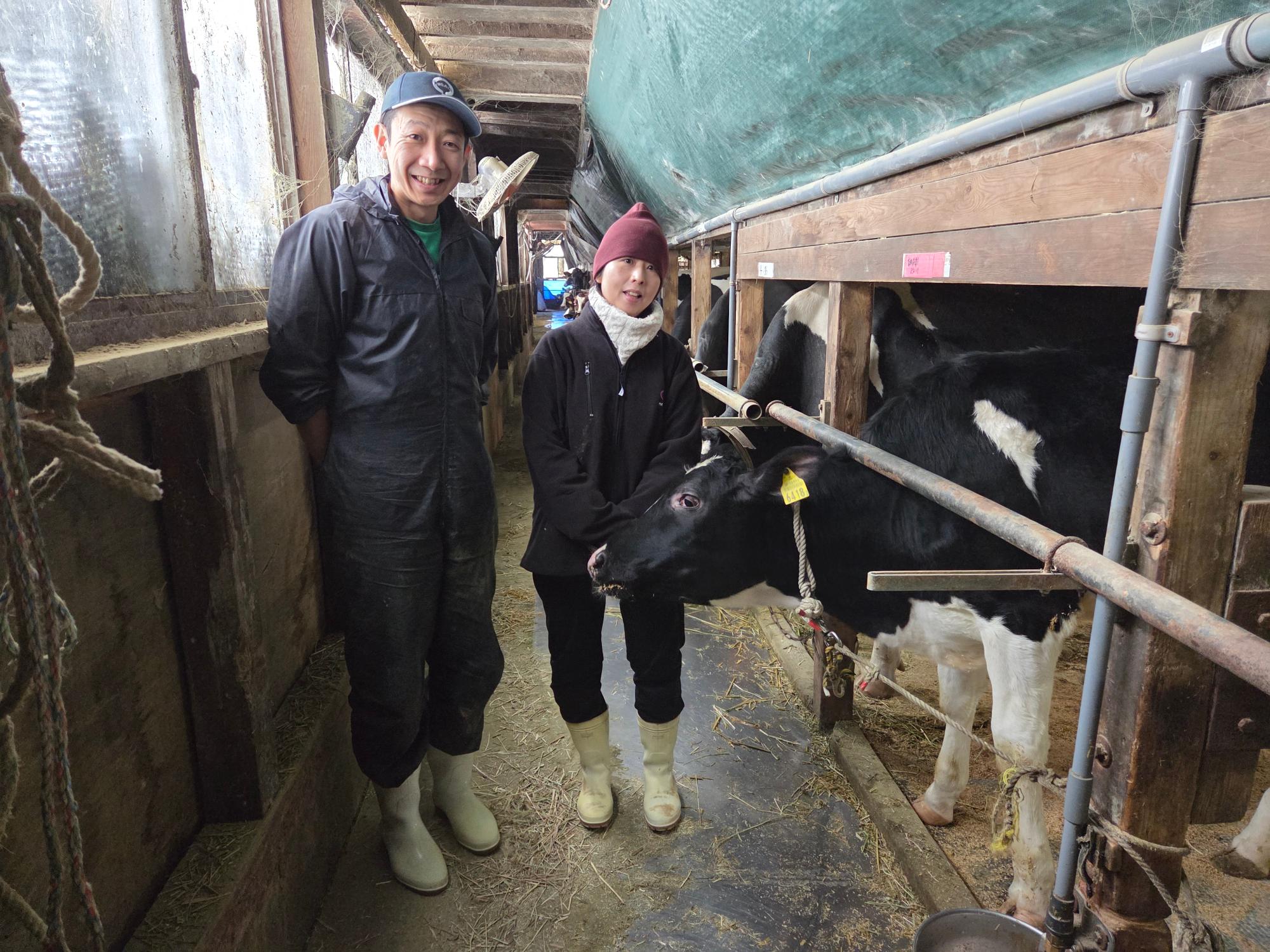 写真：牛舎の中で育てる牛を前に微笑む江部さんご夫婦