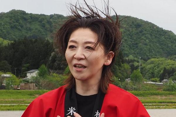 写真：アンバサダーの越乃リュウさん。強風の中でコメントしています
