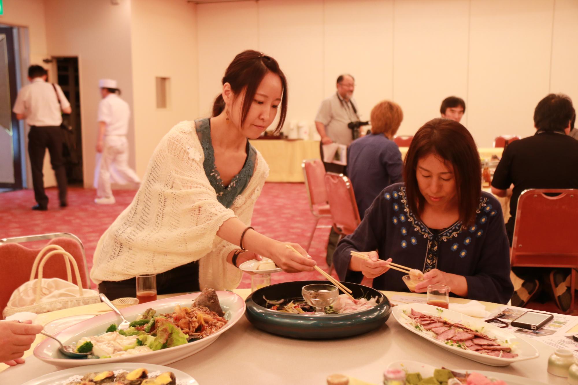 円卓に載せられたヒゲソリダイの料理を味わう2人の女性