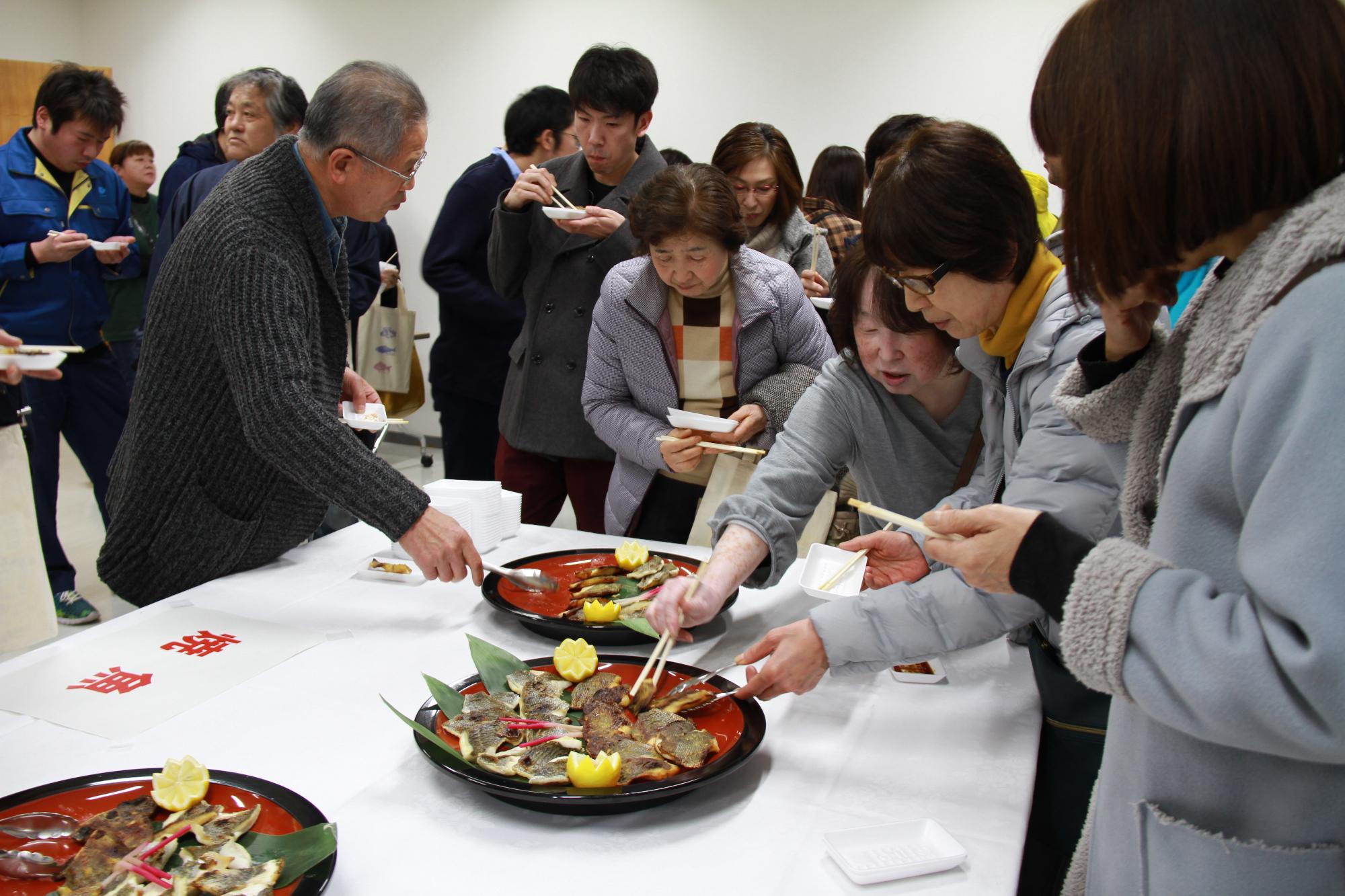 焼いたヒゲソリダイを試食しようとしている大勢の参加者