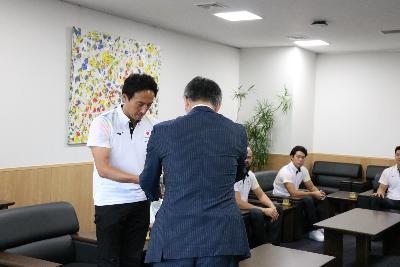 写真：櫻井市長が水球日本代表監督へ米山プリンセスを手渡しています。