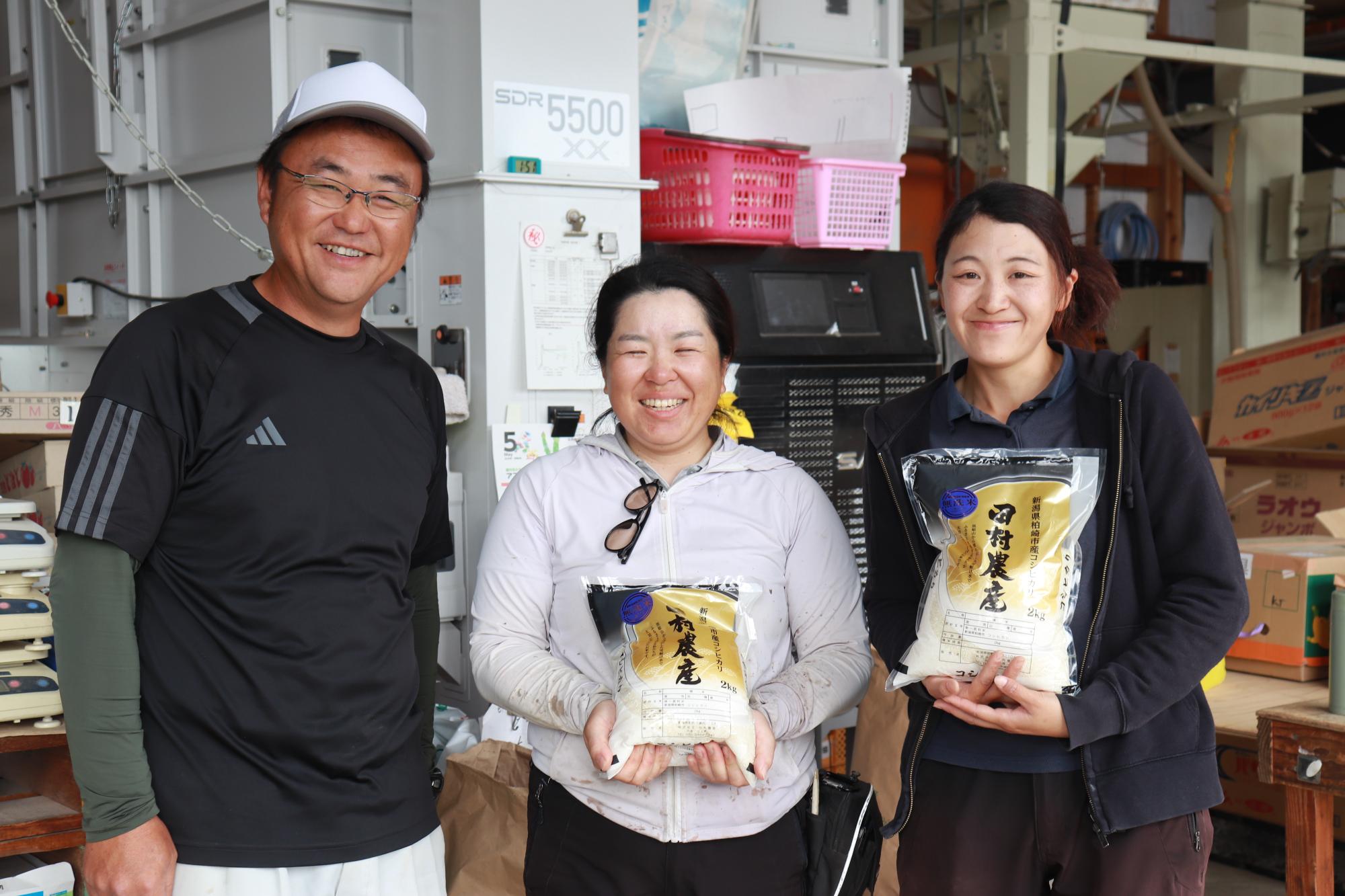 写真：笑顔で写真に写る株式会社田村農産の皆さん。真貝さんと春日さんは、田村農産と表示されたお米を持っています。