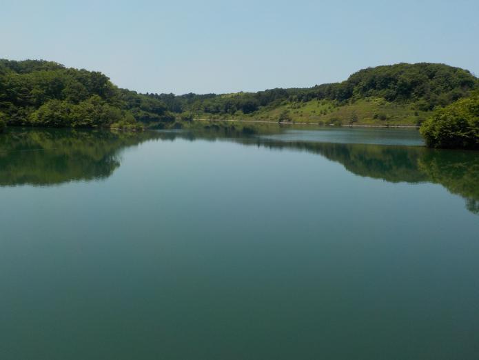 ダム湖の水に山が映し出される穏やかなダム湖上流を撮影した写真