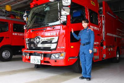 写真：消防車に手を添えて微笑む渡部さん