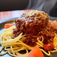 写真：スパゲティの上に肉厚のハンバーグとたっぷりのミートソースが掛かったメニュー