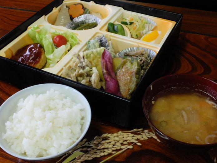 ごはんとみそ汁と地元で採れた、山菜天ぷら・ぜんまい煮などが入った日替わり定食の写真