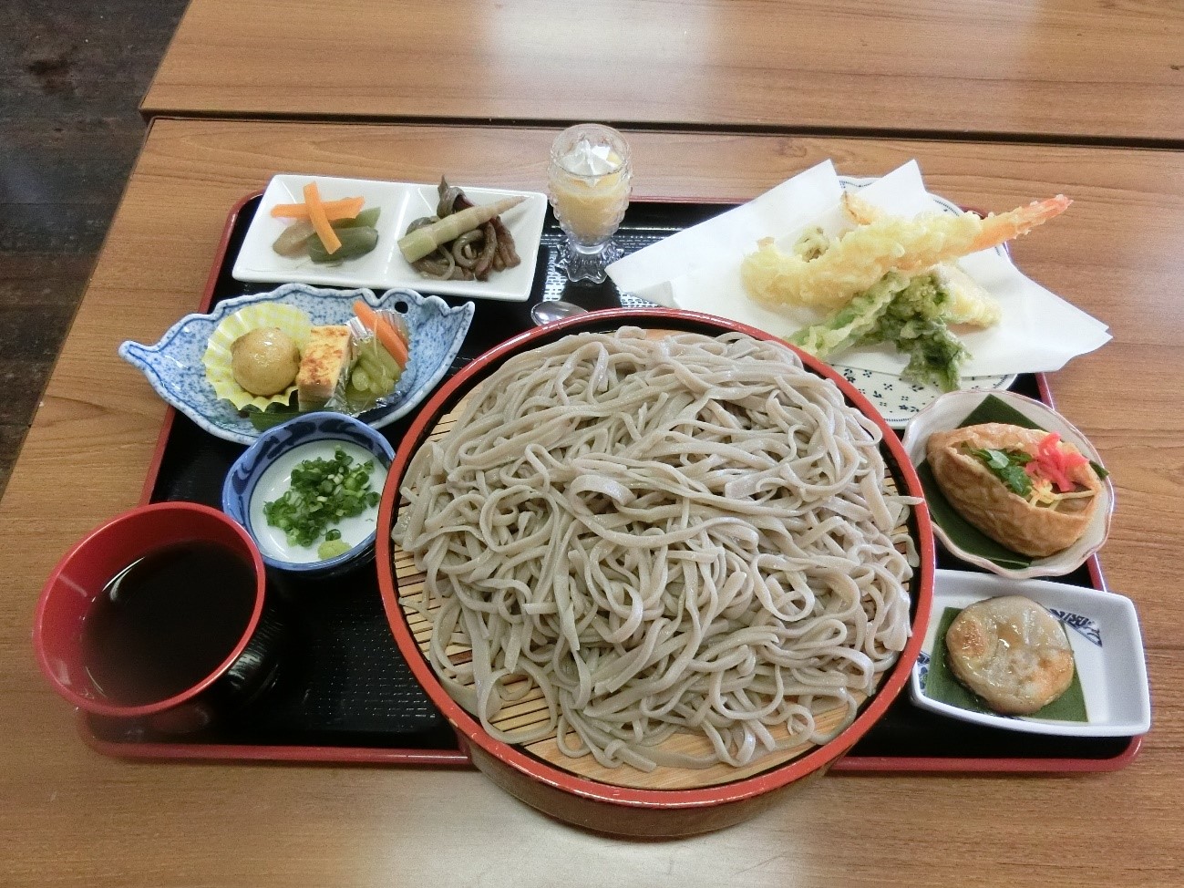 県内産そば粉を使った手打ちそばと地元でとれた山菜と野菜の小鉢の写真